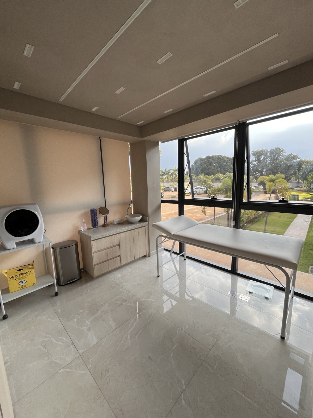 Sala de procedimentos da Clínica A. Mariotto, com maca e janela panorâmica